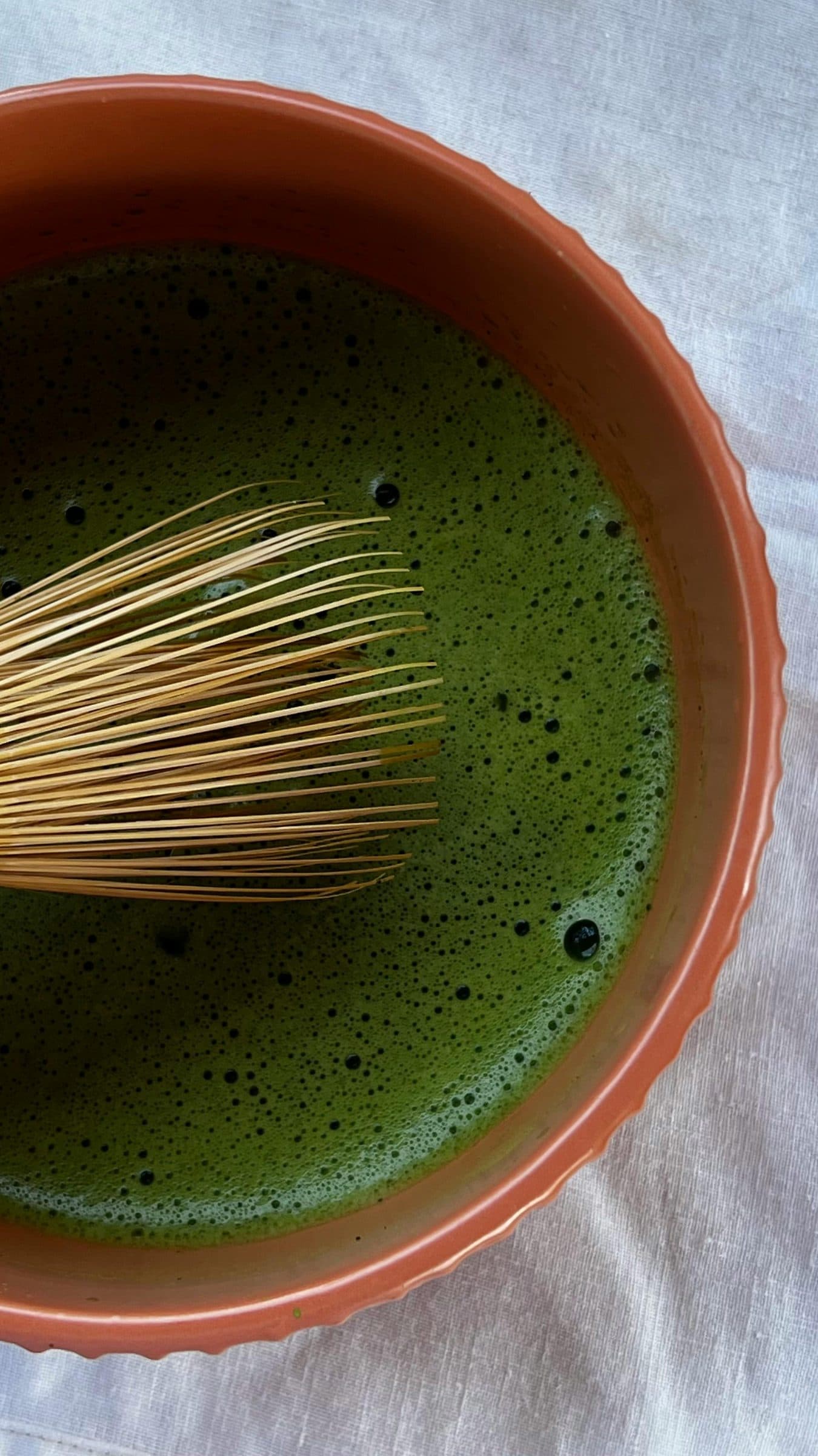 Top-down view of freshly whisked matcha in a terracotta tea bowl