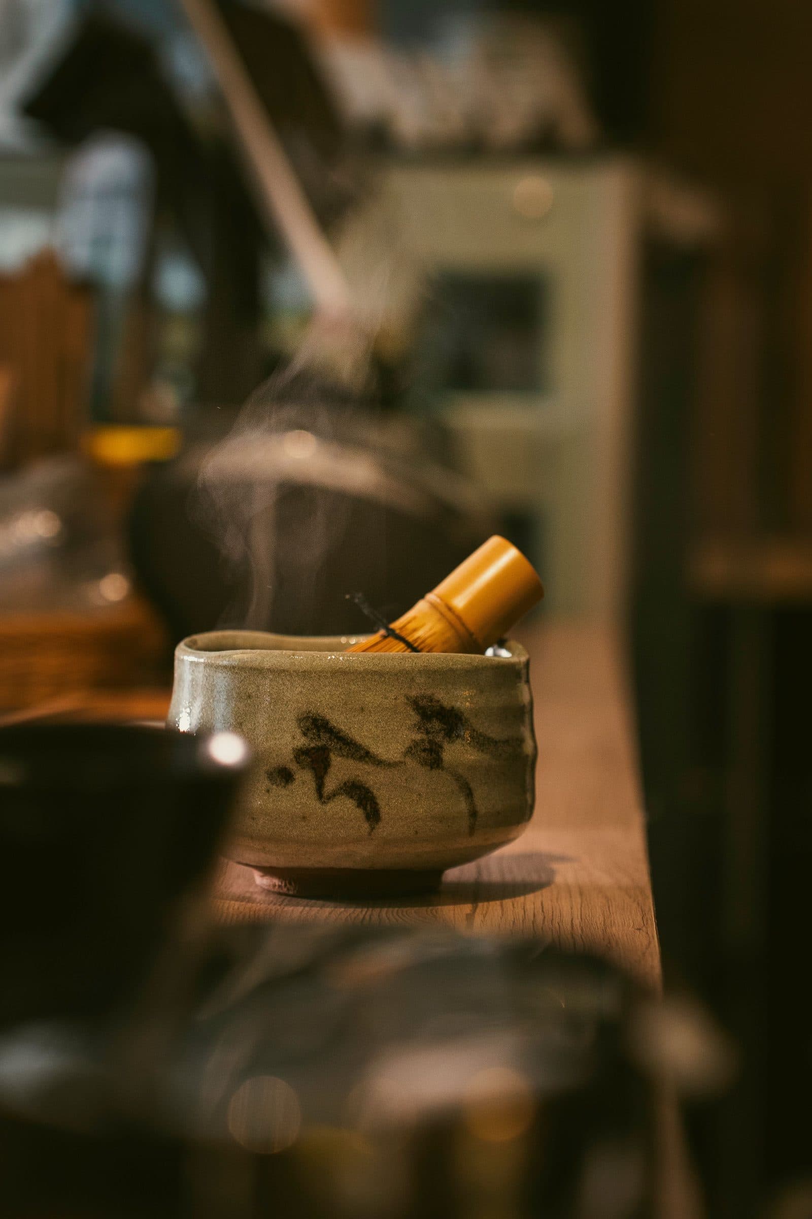 A steaming chawan tea bowl with a bamboo whisk in warm light